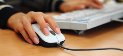 Close-up view of a woman using a computer keyboard and mouse