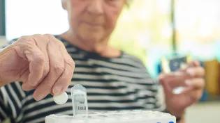 Senior woman wearing striped t-shirt takes the days tablets with a glass of water
