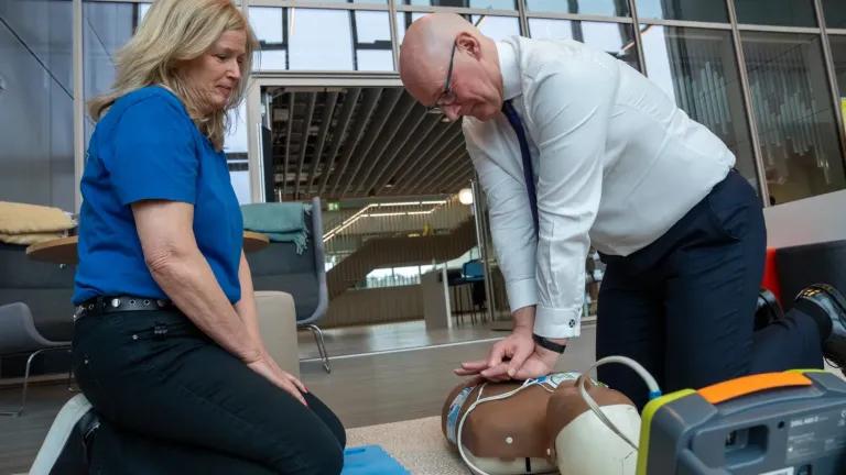 Susan Gardner from Save a Life for Scotland watches on as First Minister of Scotland John Swinney performs CPR on a manikin.  