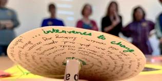 Close-up of a paper wheel, with writing on it, title says 'Intervenes to change'.