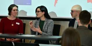 Giulia speaks into a mic on a Q&A panel as Andre and Jaime listen.