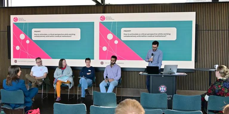 Lukas Engelmann introduces the panel, prompt on slide behind says 'How to articulate a critical perspective while working collaboratively with/within medical institutions.'