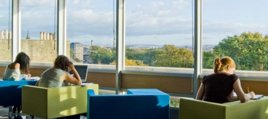 Three students studying on campus with heads down and using their laptops