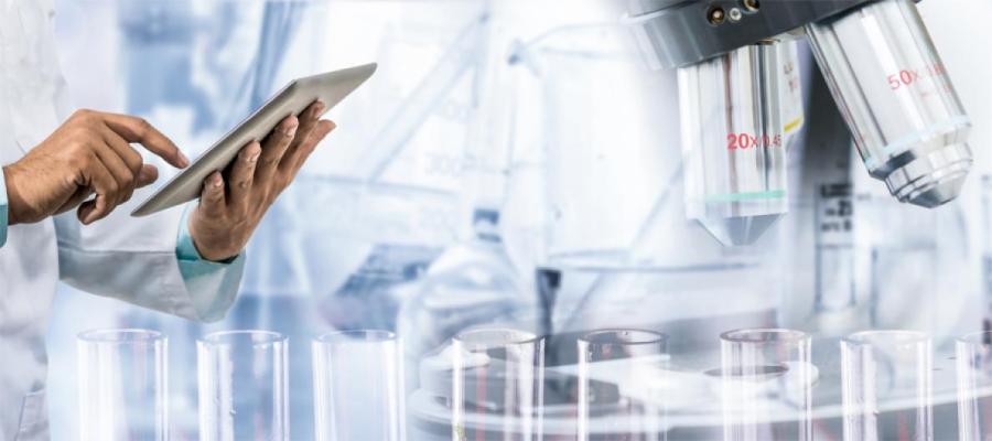 Doctor in white coat using tablet computer alongside microscope