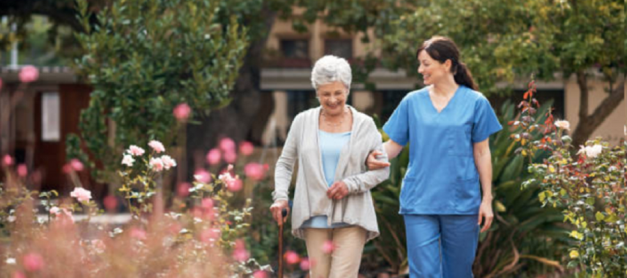 Elderly person with care worker walking in garden