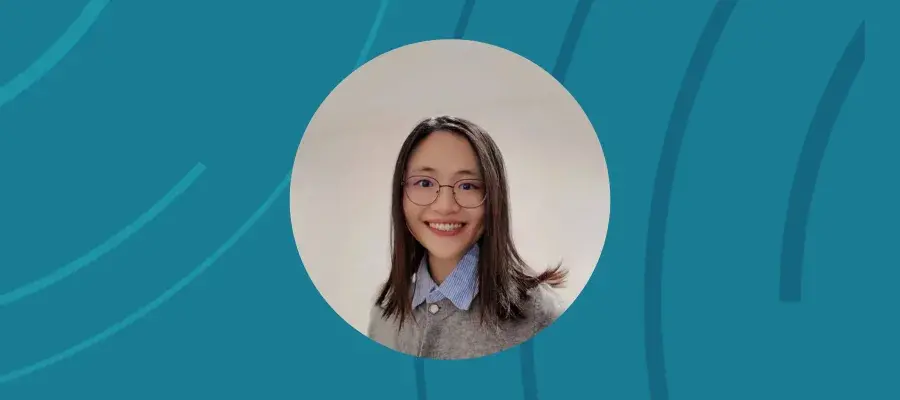 An image of a woman smiling in a circle style frame, on a blue background.