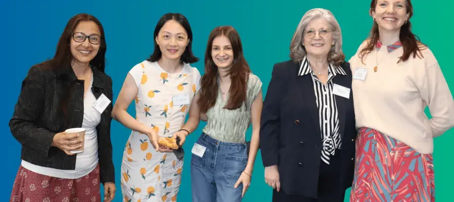 Blue green background, colour photo of various I&I female team members similing in a group