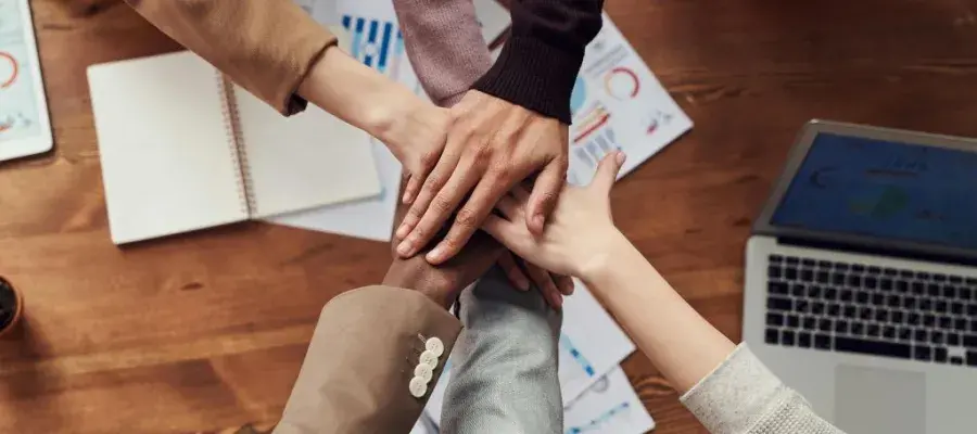 An image of several hands piled together in a team manner.