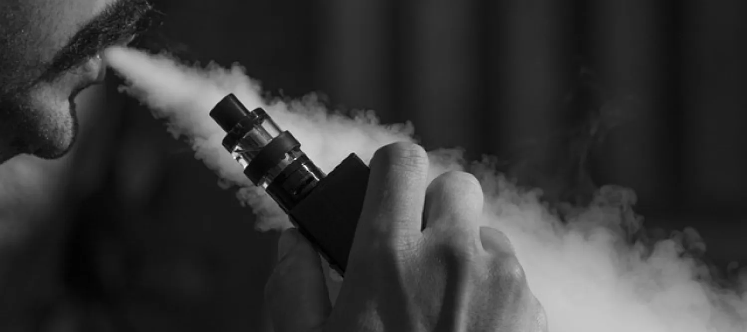 Person blowing smoke out of their mouth with a vape in their hand