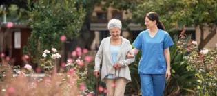 Elderly person with care worker walking in garden
