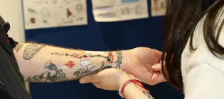 An already tattooed arm has numerous temporary tattoos applied.