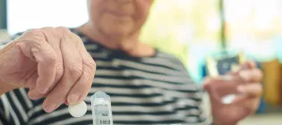 Senior woman wearing striped t-shirt takes the days tablets with a glass of water