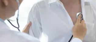 Doctor in white coat examining the lungs of patient