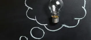 Clear Light Bulb Placed on Chalkboard