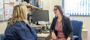 A woman is seen from behind talking to her GP