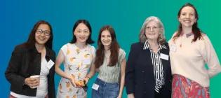 Blue green background, colour photo of various I&I female team members similing in a group