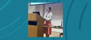 An image of a woman standing to present at a podium.