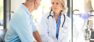 Female doctor sitting with elderly male patient