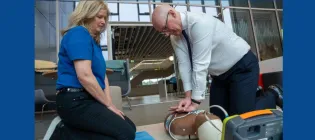 Susan Gardner from Save a Life for Scotland watches on as First Minister of Scotland John Swinney performs CPR on a manikin.  