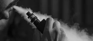 Person blowing smoke out of their mouth with a vape in their hand