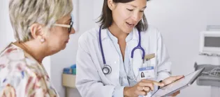 Individual speaking with a medical professional (wearing a stethoscope) lokoing at notes together