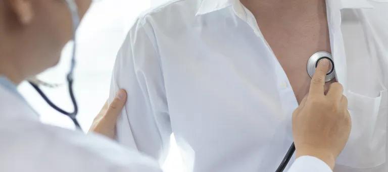 Doctor in white coat examining the lungs of patient