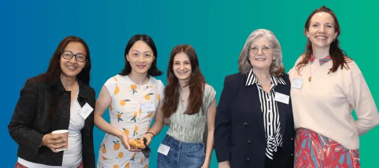 Blue green background, colour photo of various I&I female team members similing in a group