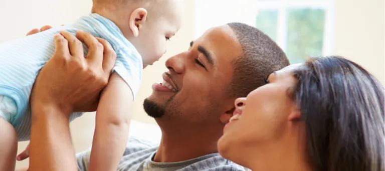 Image of parents holding up a baby