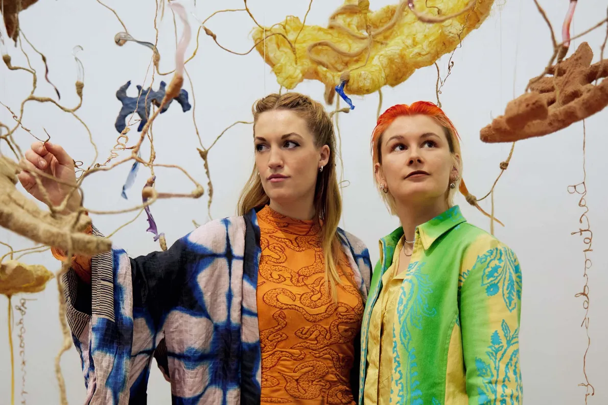 Two artists stand within their work.