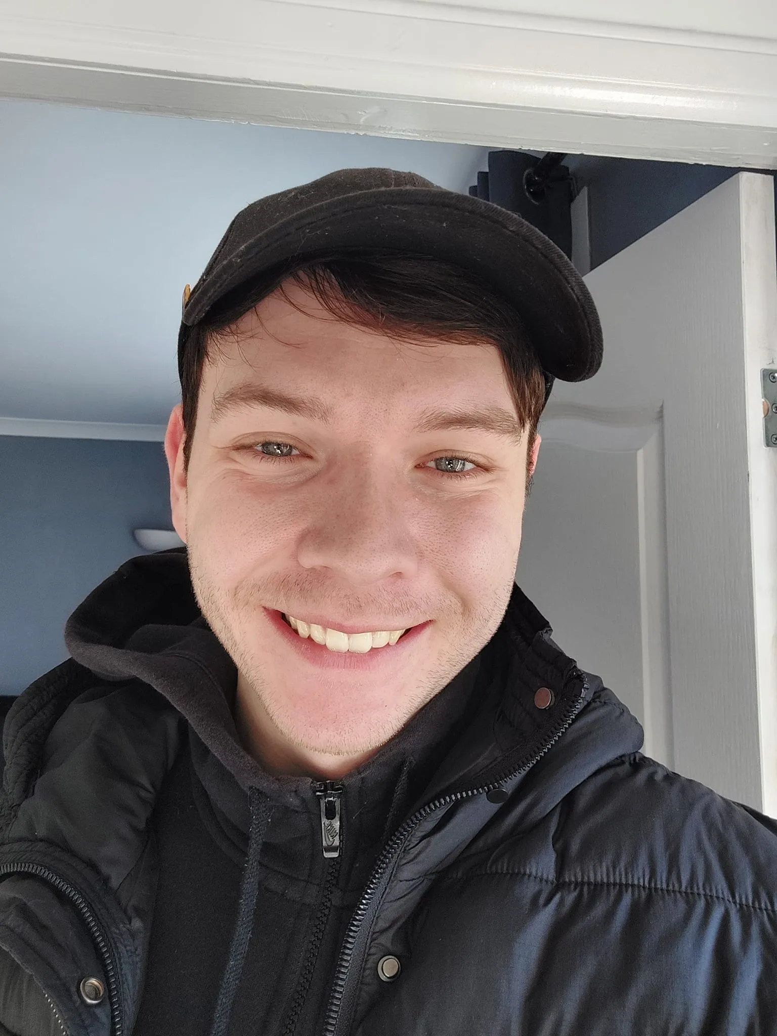 Headshot of a young man in a cap and hoodie