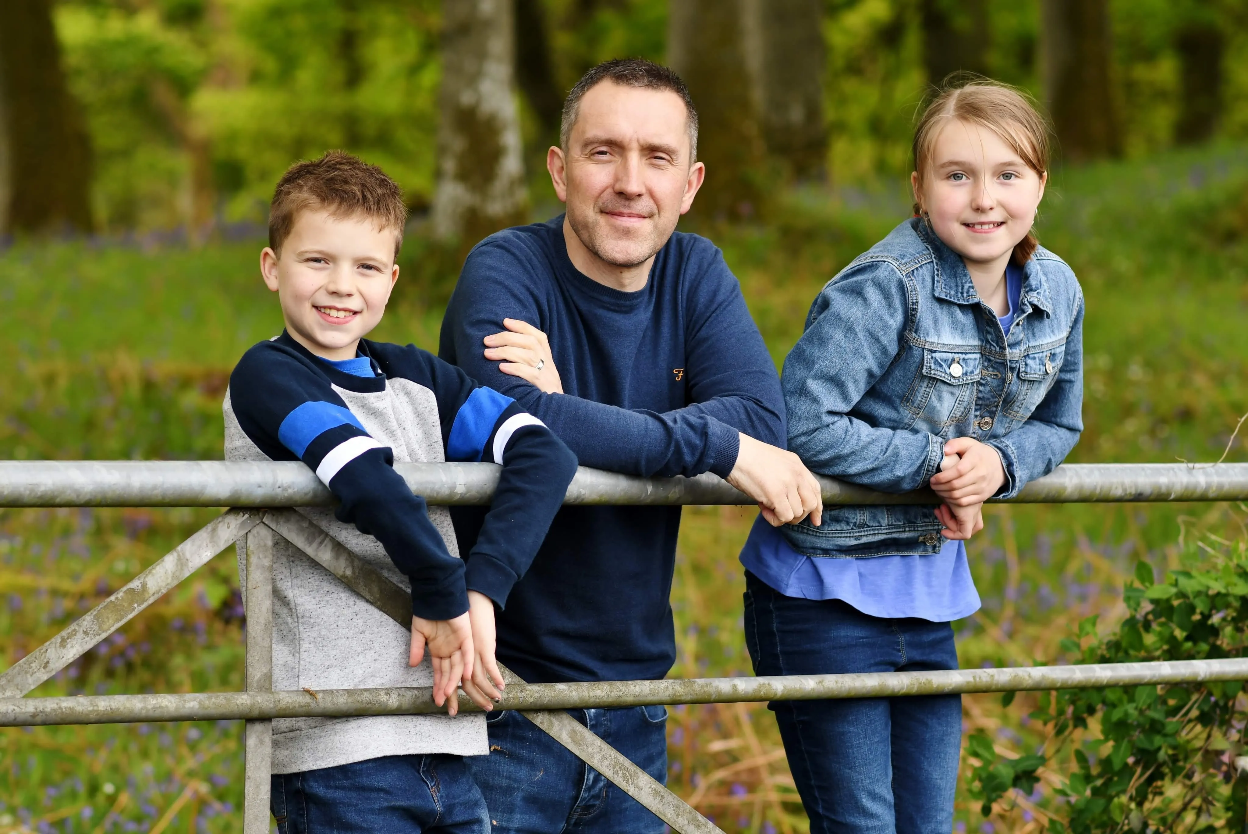 Will McLean standing by a gate with his 2 children