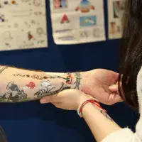 An already tattooed arm has numerous temporary tattoos applied.