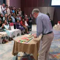 A cake being cut in front of a crowd