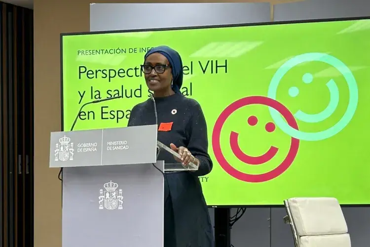 Dr Winnie Byanyima talks at a podium with the presentation behind.