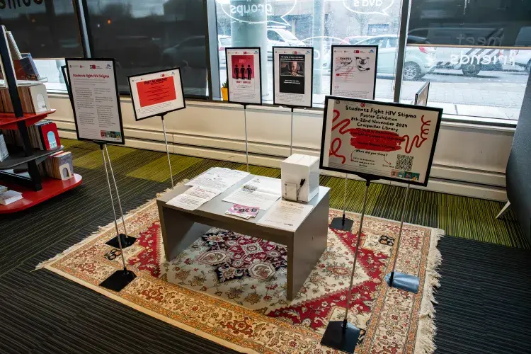 A small exhibition of posters on stands, with leaflets on the table.