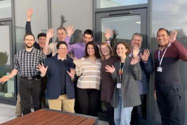 A group of ten people smiling and waving