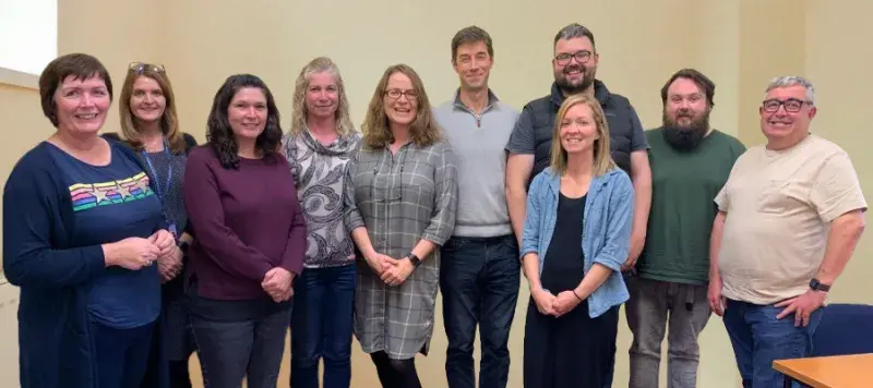 A group of 10 people standing together in a room