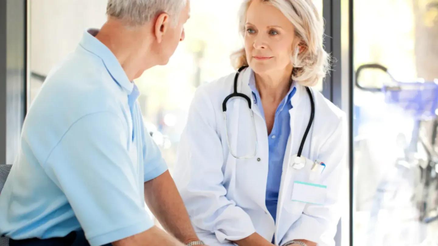 Female doctor sitting with elderly male patient