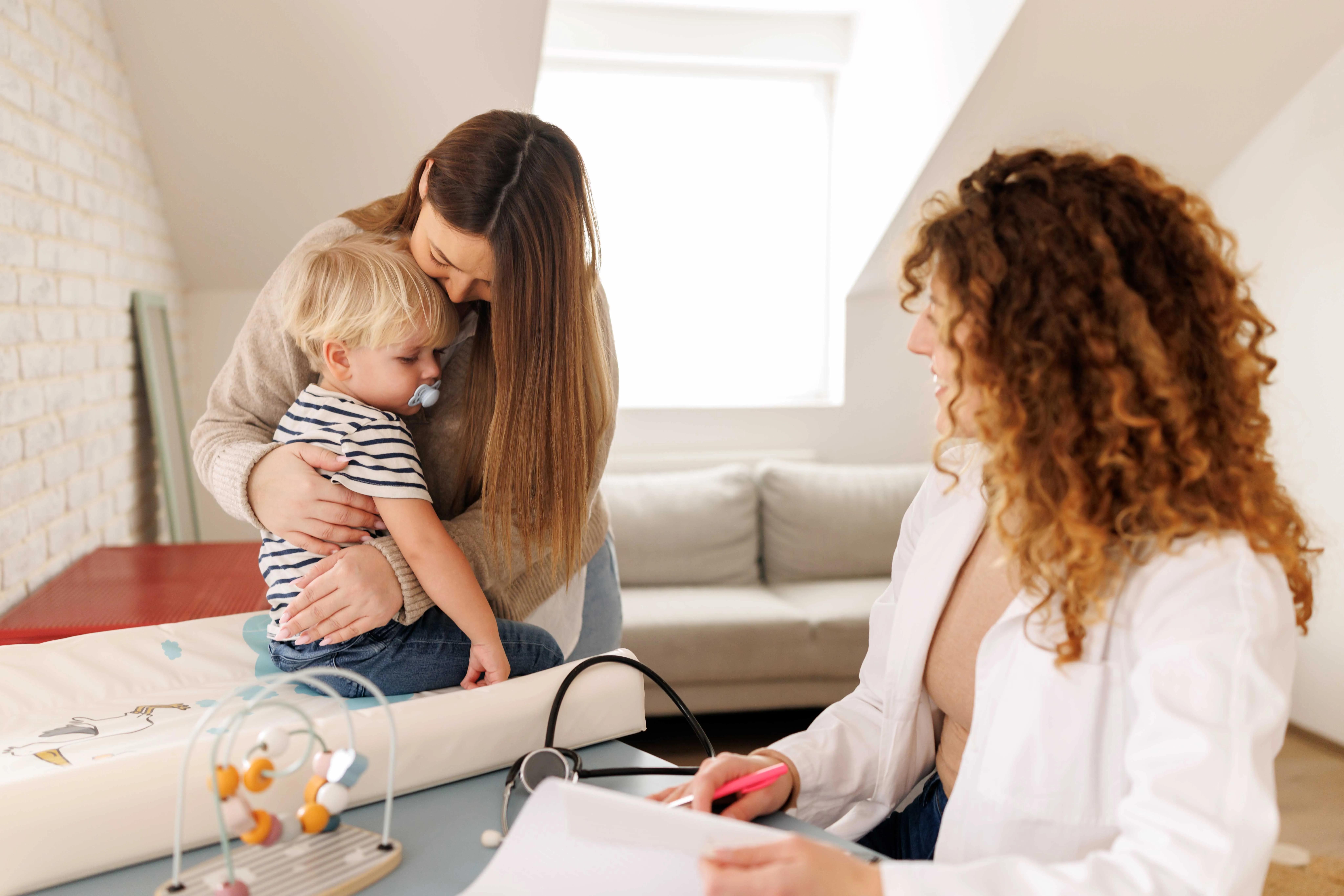Photograph of parent hugging their toddler child visiting a doctor