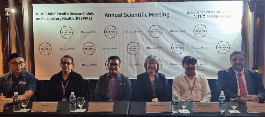 Six people sitting on a press conference panel