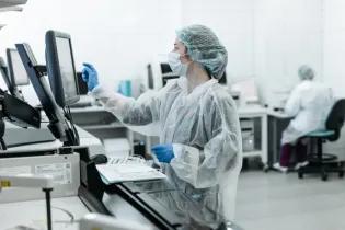 Photo of person in protective clothing operating computer in clinical setting