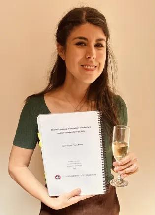 Photograph of Cecilia Prieto Bravo holding her completed PhD