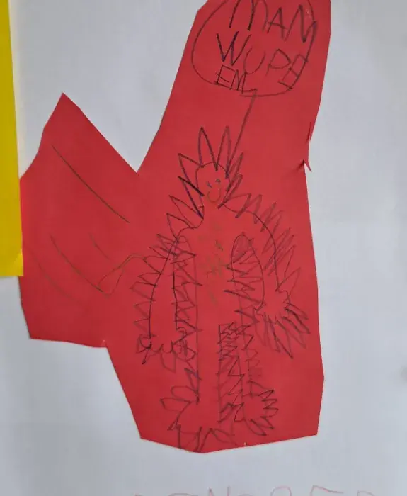 A child's drawing of a man-shaped monster with a speech bubble written in Polish.