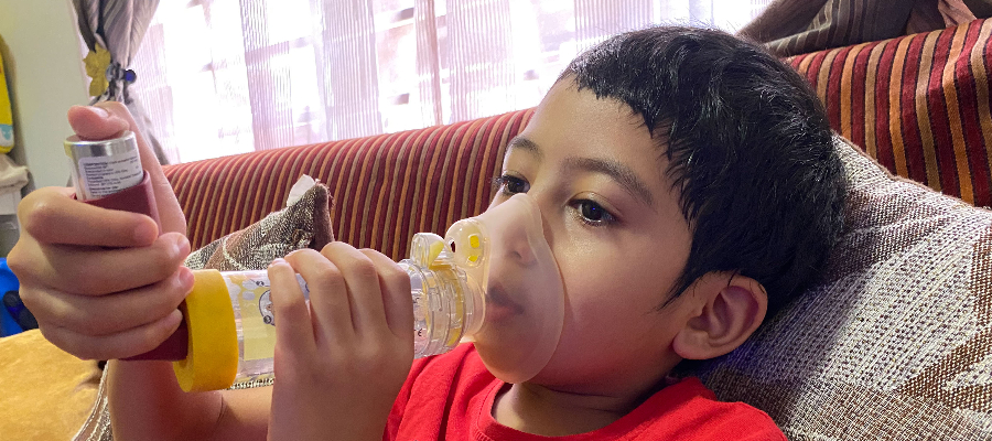 Young boy using inhaler with spacer