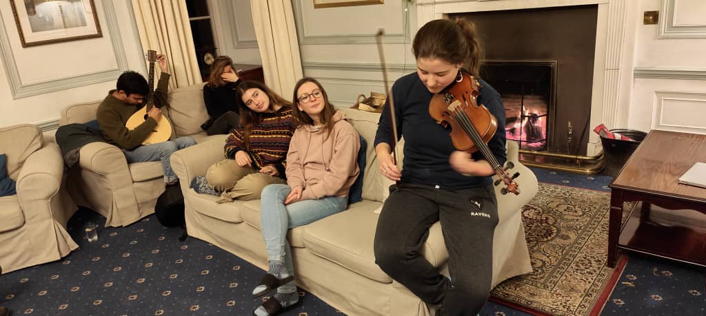 A girl plays violin while others watch.